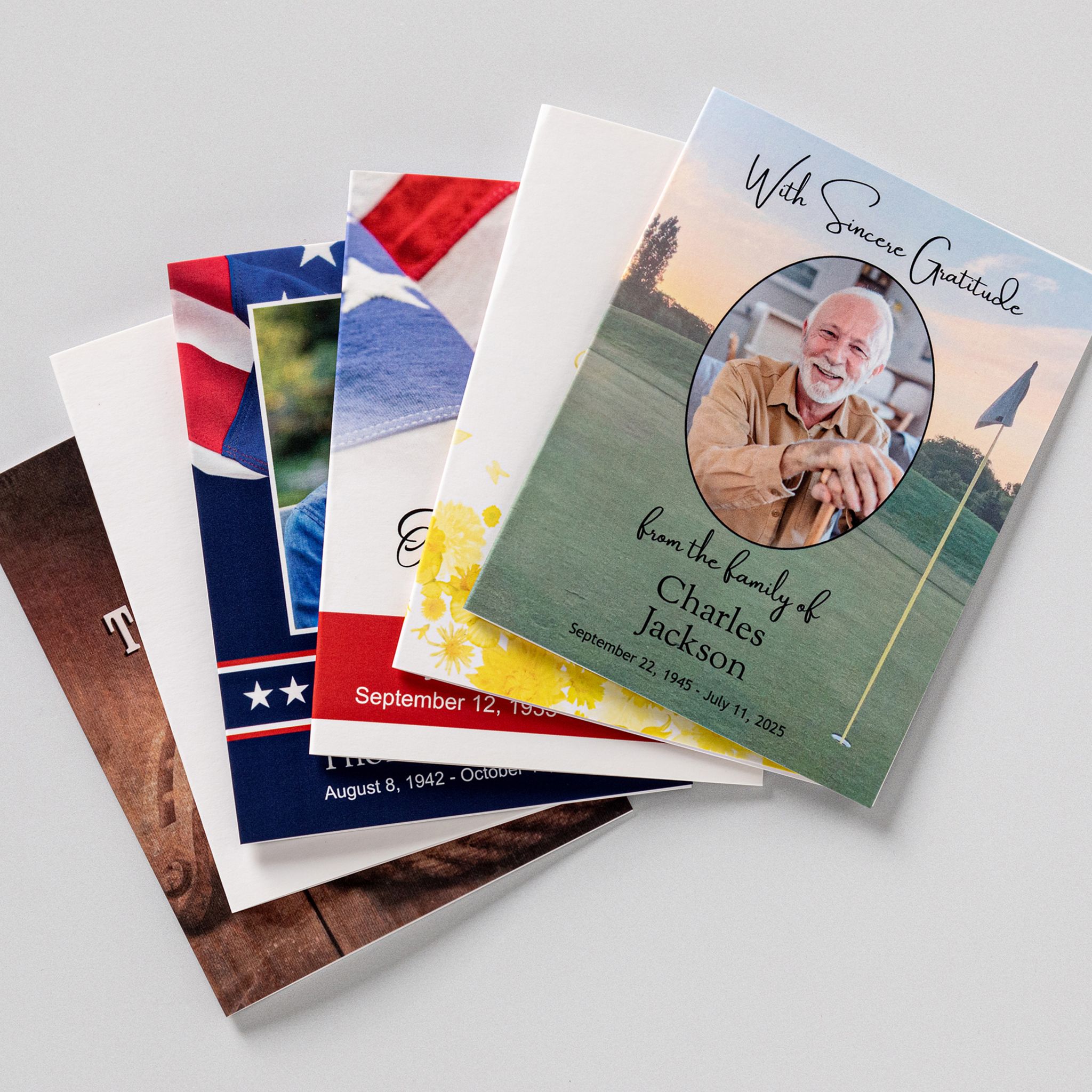 Memorial thank you cards fanned out in several designs, the top one reading With Sincere Gratitude from the family above a photograph