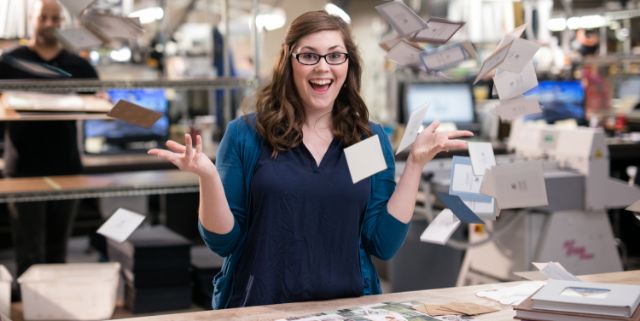 A Miller's team member laughing on the production floor as finished prints fall through the air around her