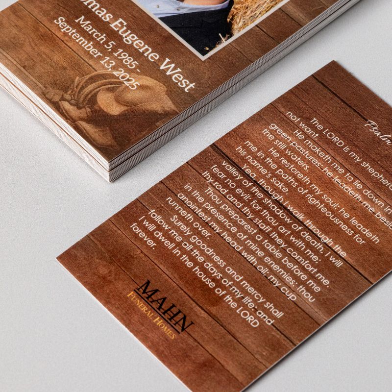 A stack of memorial prayer cards beside a single card turned over to its Psalm 23 side