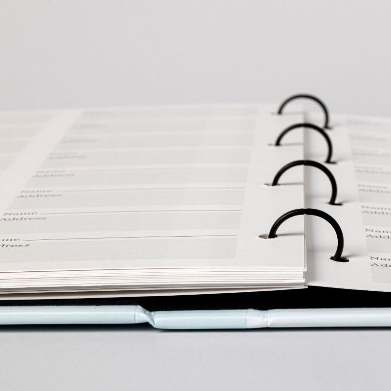 The four-ring binding of a memorial registration binder, holding guest register pages that lie flat for signing