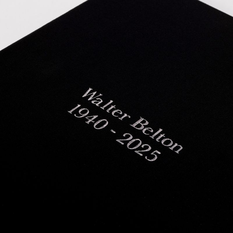 Close view of a black linen registration binder cover debossed in silver with a name and dates